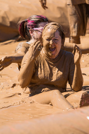 Hampton, GA, USA - April 23, 2016:  A woman covered in mud laughs after sliding into a pit of muddy...