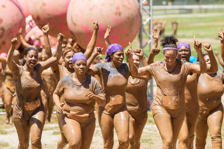 Hampton, GA, USA - April 23, 2016:  A group of muddy women celebrate with raised arms as they jog toward the finish line of the Dirty Girl Mud Run obstacle course event on April 23, 2016 in Hampton, GA.のeditorial素材