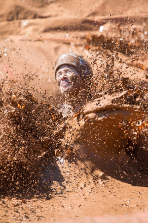 Hampton, GA, USA - April 23, 2016:  A woman creates a big splash of muddy water as she lands in a...