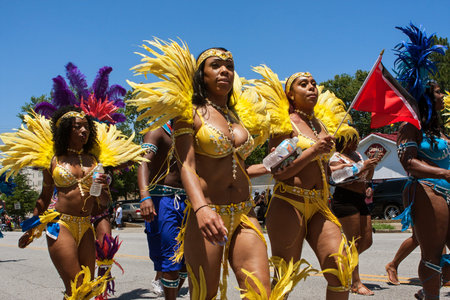 Atlanta, GA, USA - May 28, 2016:  Women wearing yellow bikinis and elaborate feathered costumes walk...
