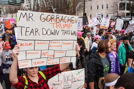 Atlanta, GA, USA - January 21, 2017:  A woman carries a sign that says "Mr. Trump, tear down this wall" as she and thousands of others participate in the Atlanta march for social justice and women, the day after President Trump's inauguration, on January のeditorial素材