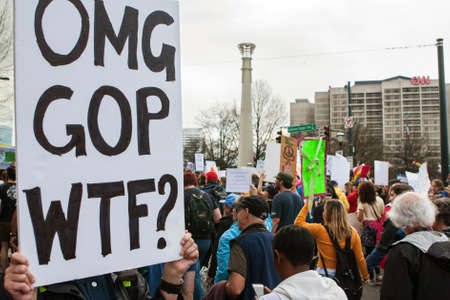 Atlanta, GA, USA - January 21, 2017:  A woman holds a sign that says "OMG, GOP, WTF?" as thousands of protesters pass by in the Atlanta march for social justice and women, the day after President Trump's inauguration, on January 21, 2017 in Atlanta, GA.のeditorial素材