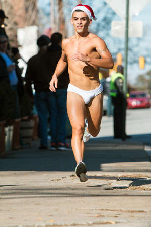 Atlanta, GA, USA - December 10, 2016:  A male runner wearing a white speedo swimsuit jogs down a city street at the Santa Speedo Run, an annual charity fundraiser, on December 10, 2016 in Atlanta, GA.のeditorial素材