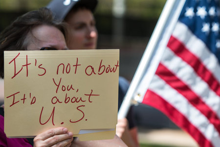 Atlanta, GA - April 15, 2017:  A woman holds sign that says It's not about you, it's about U.S. as...