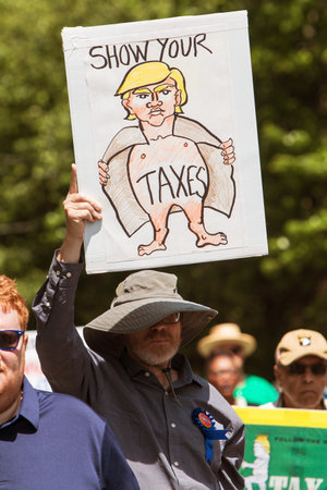 Atlanta, GA - April 15, 2017:  A man holds sign that says "Show your taxes" that shows cartoon image of Trump as a flasher, at the Atlanta Tax Protest on April 15, 2017 in Atlanta, GA.のeditorial素材