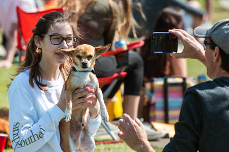 Suwanee, GA, USA - May 6, 2017:  A young woman lifts her chihuahua up to take a smartphone photo at   Woofstock, a dog festival at Suwanee Town Center on May 6, 2017 in Suwanee, GA.のeditorial素材