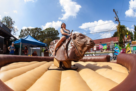 Atlanta, GA, USA - September 23, 2017:  A young woman tries to stay upright as she rides a mechanical bull at the East Atlanta Strut, a fall festival on September 23, 2017 in Atlanta, GA.のeditorial素材