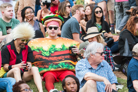 Atlanta, GA, USA - October 21, 2017:  A man wearing a hamburger costume sits with a crowd of...