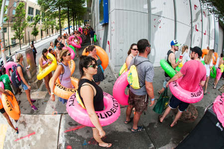 Atlanta, GA, USA - July 15, 2017:  People carrying innertubes stand in a long line stretching around a city block, waiting for their turn on the water slide at the Slide The City event, on July 15, 2017 in Atlanta, GA.のeditorial素材