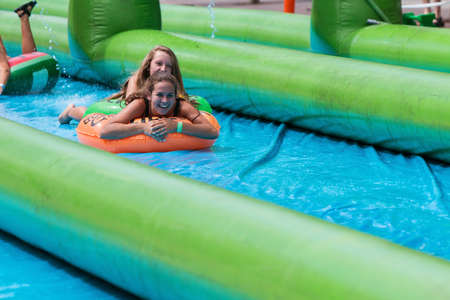 Atlanta, GA, USA - July 15, 2017:  Teenage girls laugh as they travel down a giant slip-and-slide in an innertube, at the Slide The City event on July 15, 2017 in Atlanta, GA.のeditorial素材