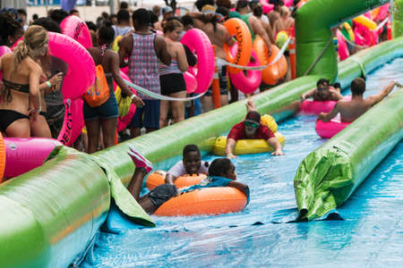 Atlanta, GA, USA - July 15, 2017:  People carrying innertubes stand in a long line waiting their turn and watch others slide downhill at the Slide The City event, on July 15, 2017 in Atlanta, GA.のeditorial素材