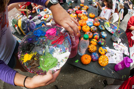 Alpharetta, GA, USA - September 30, 2017:  A woman squirts oil paint onto a palette to paint miniature pumpkins at the Scarecrow Harvest fall festival on September 30, 2017 in Alpharetta, GA.のeditorial素材