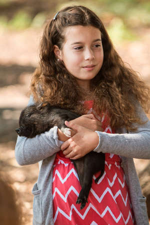 Alpharetta, GA, USA - September 30, 2017:  A grade school girl lovingly holds a sleeping piglet at the petting zoo at the Scarecrow Harvest Festival on September 30, 2017 in Alpharetta, GA.のeditorial素材