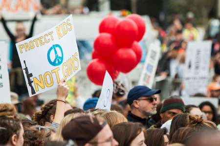 Atlanta, GA, USA - March 24, 2018:  A hand holds a sign above the crowd that reads "Protect kids...not guns" at the Atlanta March For Our Lives gun protest and rally, on March 24, 2018 in Atlanta, GA.のeditorial素材