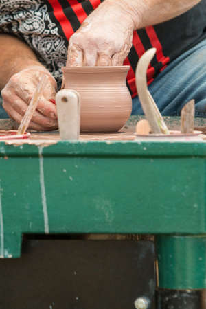 Lawrenceville, GA, USA - April 28, 2018:  Closeup shows pottery artist's hands forming a bowl with his hands while spinning a pottery wheel as part of a live demonstration at the Lawrenceville Arts Fest on April 28, 2018 in Lawrenceville, GA.のeditorial素材