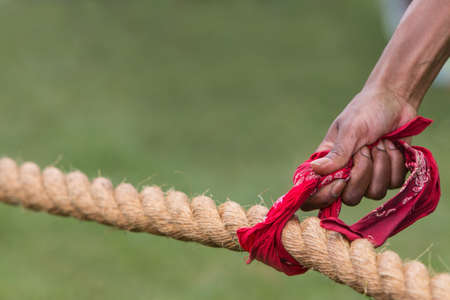 A hand holds a bandana attached to a thick rope before the start of a tug of war contest.の写真素材