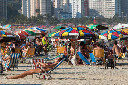 Sao Vicente, Brazil - July 8, 2018:  Hundreds of Brazilian people and dozens of colorful umbrellas crowd the beach on a hot summer day on July 8, 2018 in Sao Vicente, Brazil.のeditorial素材