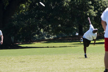 Atlanta, GA, USA - July 28, 2018:  A man slings a frisbee with great effort as his team "kicks off" to the other team in an ultimate frisbee game in Piedmont Park on July 28, 2018 in Atlanta, GA.のeditorial素材