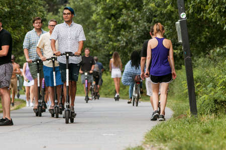 Atlanta, GA, USA - July 6, 2019:  Young men ride motorized scooters along the Atlanta Beltline at the Old Fourth Ward Park, on July 6, 2019 in Atlanta, GA.のeditorial素材