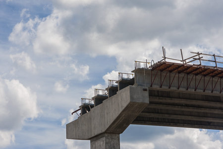 Partially constructed bridge overpass sits framed against a partly cloudy sky