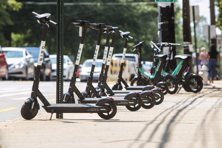 Atlanta, GA, USA - August 10, 2019:  Several motorized scooters sit lined up and parked on a...