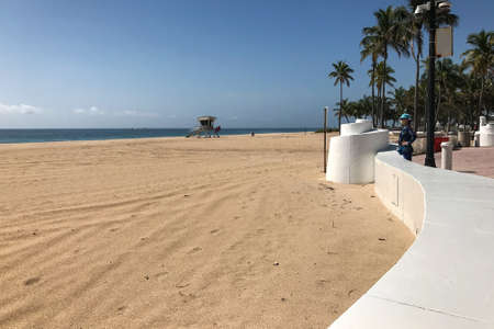 Fort Lauderdale, Florida / USA - May 21, 2020:  A lone woman wearing a mask looks out on a completely empty beach, as beaches remain closed for the Covid-19 pandemic public health crisis, on May 21, 2020 in Fort Lauderdale, Florida.のeditorial素材