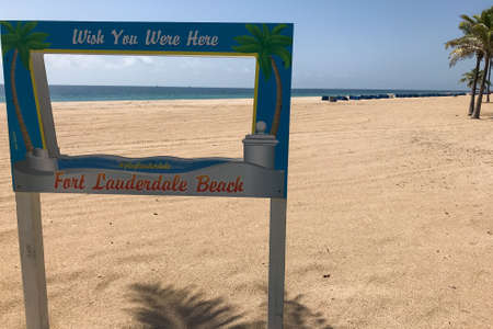 Fort Lauderdale, Florida / USA - May 21, 2020: A sign reading "Wish you were here" sits on a vast, empty, humanless beach as beaches remain closed for the Covid-19 pandemic crisis, on May 21, 2020 in Fort Lauderdale, Florida.のeditorial素材
