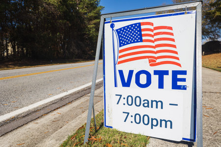 A sign by road gives the hours available to vote at that voting precinct.の写真素材
