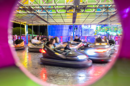 Bumper cars at a carnival midway motion blur, as unrecognizeable people enjoy the ride.