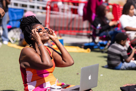 Atlanta, GA / USA - April 8, 2024:  A woman uses special glasses to see the total solar eclipse at a...