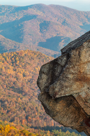 Vertical shot shows a jagged rock formation sticking out from atop a mountain, with pretty fall...