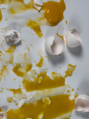 Messy cracked eggs on white seamless background create abstract background plate.