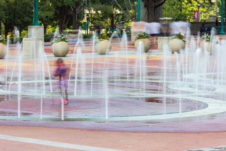 Motion blur shows a lone kid playing in Centennial Olympic Park fountain on a hot summer day on August 26, 2023 in Atlanta, GA.の写真素材