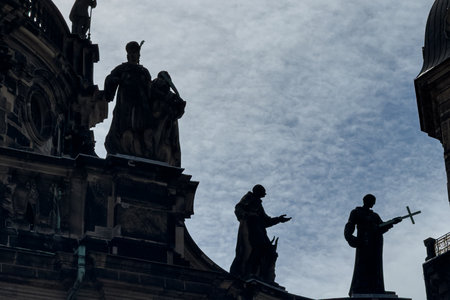 Several baroque statues are silhouetted against the sky atop a medieval building in Dresden, Germany.の写真素材