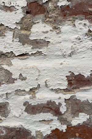 White paint peeling off weathered red brick on a medieval buidling creates an interesting textured...