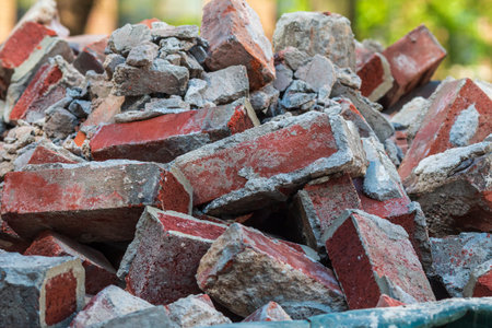 Closeup shows discarded red bricks sitting piled up in a dumpster at a construction site.の写真素材