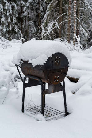 An old bbq grill covered in snowの写真素材