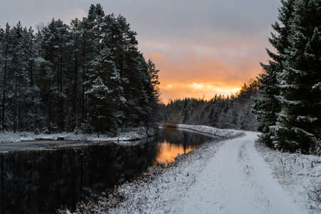 a channel with a snowy road and a red skyの写真素材