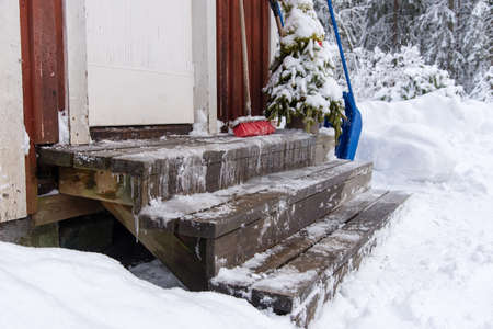 icy stairs infront of a red wooden house in varmland swedenの写真素材