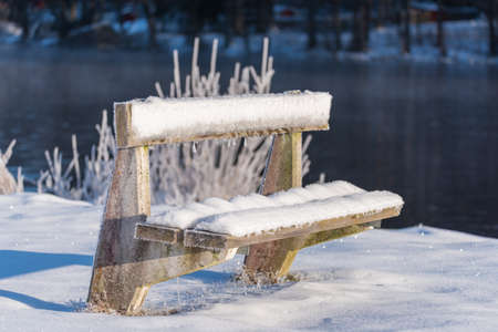 a cold and frozen bench covered in snow in swedenの写真素材