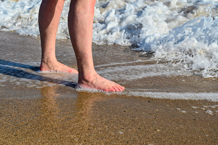 human standing in water on a sand beach
