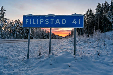 road sign near winter road through Varmland Swedenの写真素材