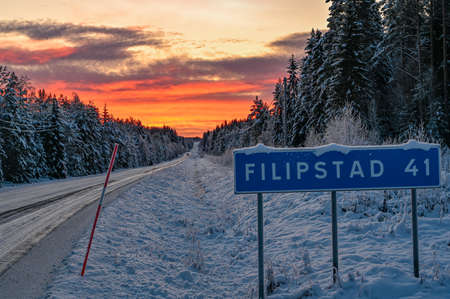 road sign near winter road through Varmland Swedenの写真素材