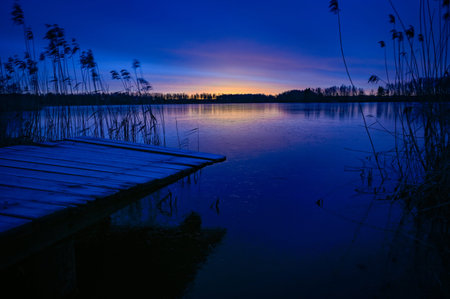 sunrise over wooden jetty and frozen lake
