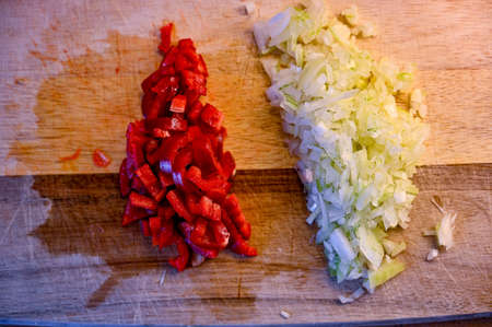 preparing onion and red pepper on a wooden cutting boardの写真素材