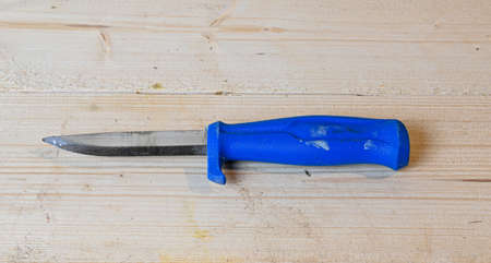 knife with blue plastic handle on wooden working benchの写真素材