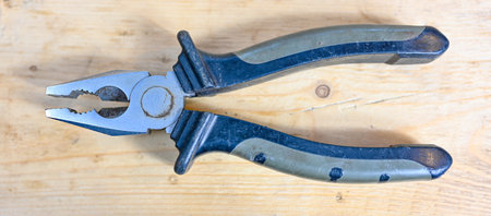 pincers with rubber handle on wooden working bench