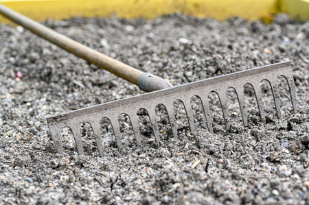 old rake lying in cultivation box in gardenの写真素材