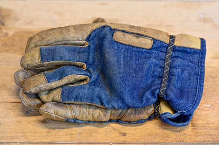 working glove with denim lying on wooden benchの写真素材
