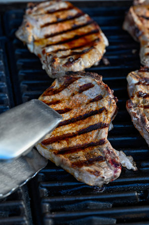 pork chop on grill and grill tongs